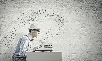 Young funny man in glasses writing on typewriter